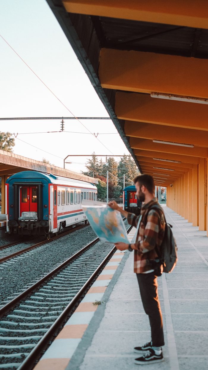 A man reading a map while waiting at a train station platform.