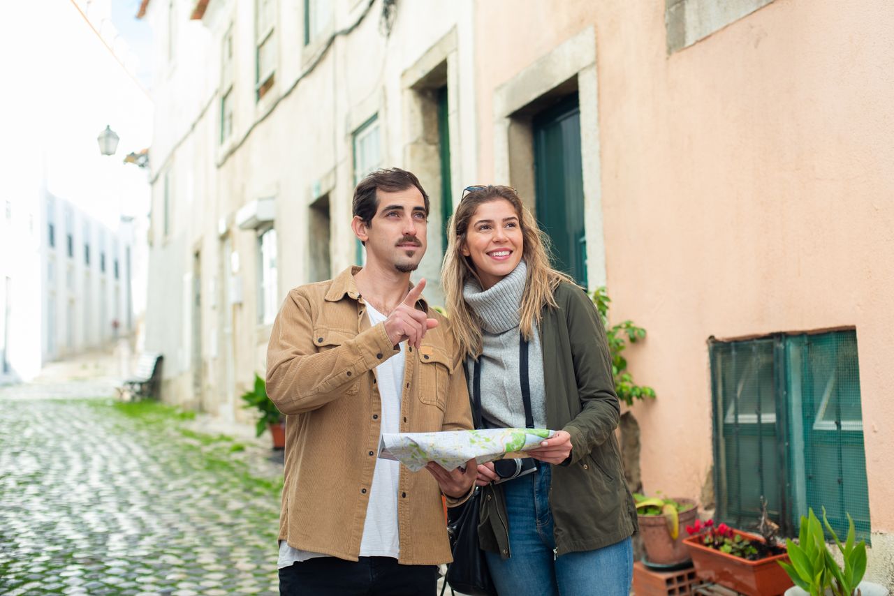 Happy couple exploring a historic city using a map, enjoying a travel adventure together.